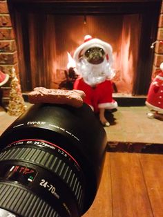 a person dressed as santa claus taking a photo in front of a fire place with a camera