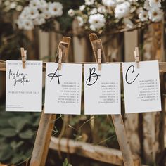 three pieces of paper hanging from clothes pegs in front of white flowers and greenery