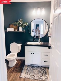 a white toilet sitting next to a bathroom sink under a round mirror on top of a wooden floor