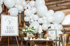 a table topped with balloons and desserts next to a sign that says ski lodge