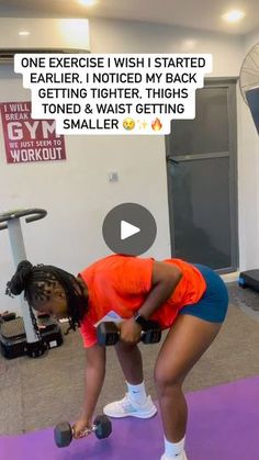 a woman is bent over while holding two dumbbells