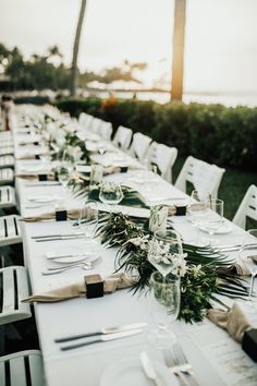 the table is set with place settings and silverware for an elegant wedding reception at sunset