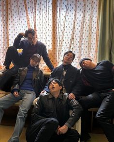 a group of young men sitting next to each other on top of a couch in front of a window