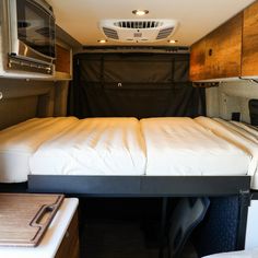 a bed in the back of a camper with a microwave and toaster oven