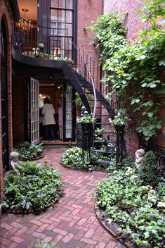 a brick building with stairs and plants growing on the side walk, surrounded by greenery