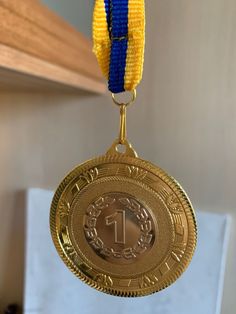 a gold medal with a blue and yellow ribbon hanging from it's center piece