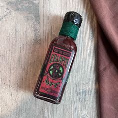 a bottle of hot sauce sitting on top of a wooden table next to a cloth