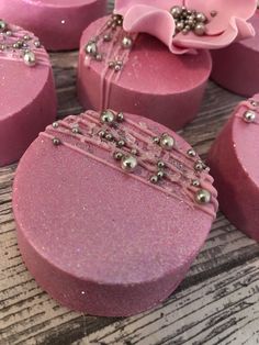 several pink soaps with pearls on them sitting on top of a wooden table next to a flower