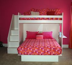 a white bunk bed with pink and orange pillows on it's bottom shelf next to a red wall