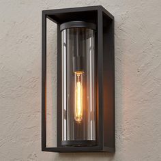 an outdoor light that is mounted on the side of a wall with a bulb attached to it