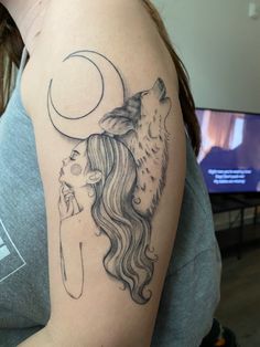 a woman's arm with a wolf and half moon tattoo on her left shoulder