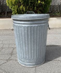 a large metal trash can sitting on top of a sidewalk