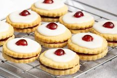 small cookies with white icing and cherries on a cooling rack