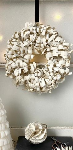 a wreath made out of books is hanging on the wall next to a table with other decorations