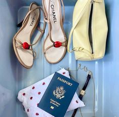 the contents of a suitcase including a passport, purse and shoes are laid out on top of each other