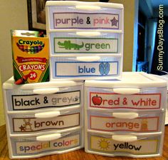 four plastic containers with labels on them sitting on top of a wooden table next to a can of crayons