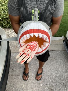 a man is holding a pumpkin shaped like a shark's mouth with blood on it