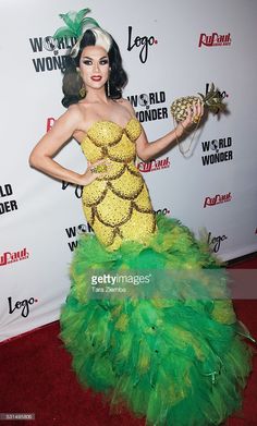 a woman in a green and yellow dress poses on the red carpet at an event