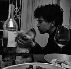 a man sitting at a table with food and wine