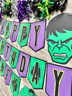 a birthday banner with the hulk face on it and purple, green and black decorations