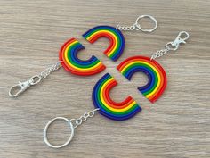 two multicolored key chains on a wooden table with metal hooks and rings hanging from them