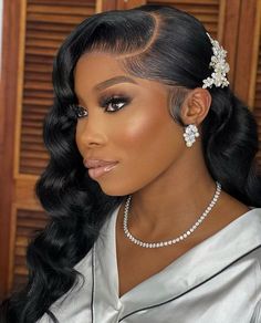 a woman with long hair wearing a silver dress and pearls in her hair is looking off to the side