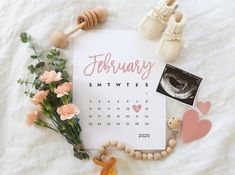 an image of a calendar with flowers and baby's shoes on the table next to it