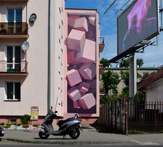 a scooter parked in front of a building with a large painting on it