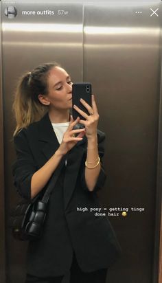 a woman taking a selfie in an elevator with her cell phone up to her ear