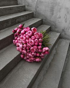 a bouquet of pink flowers sitting on top of some concrete steps next to a set of stairs