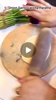 someone is cutting asparagus on top of a wooden board with a piece of bread