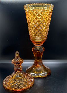 two yellow glass vases sitting next to each other on a black counter top,