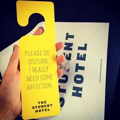 a person holding up a yellow door hanger that says, please do disturb i really need some affection