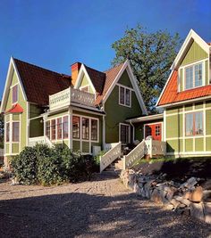 two green houses with red roof tops and white trim on the windows, along side a gravel driveway