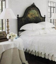 a bed with white linens and pillows in a bedroom next to two lamps on either side of the bed