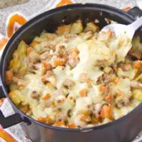 a casserole dish with meat, cheese and vegetables is being spooned into it