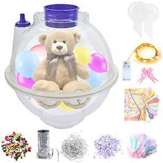 a teddy bear in a clear container surrounded by confetti and other items to decorate it