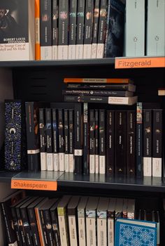 several books are on the shelves in a book store with orange and black covers,