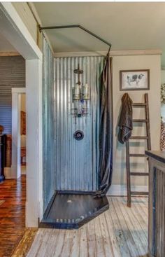 a bathroom with a shower and wooden flooring next to a ladder on the wall