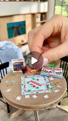 a person playing monopoly on a small table in a room with chairs and other furniture