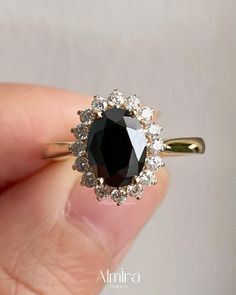 a close up of a person's hand holding a black and white diamond ring