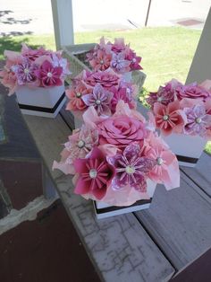 three vases with pink flowers are sitting on a bench