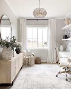 a living room with white furniture and a chandelier hanging from the ceiling over a window