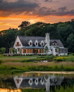 a large white house sitting on top of a lush green field next to a lake