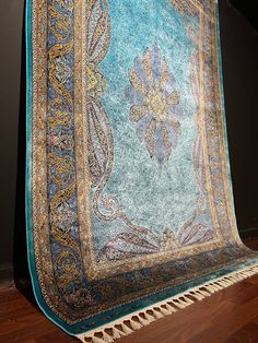 a large blue and gold rug sitting on top of a wooden floor next to a wall