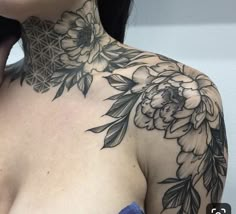 a woman's chest with flowers and leaves tattooed on her upper half sleeve,