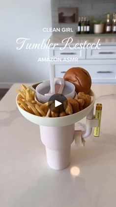 a white counter top with a hamburger and fries in a cup on it, next to a measuring tape