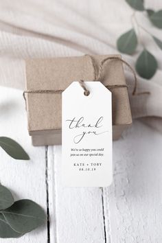 a small gift box with a tag that says thank you on it next to some eucalyptus leaves