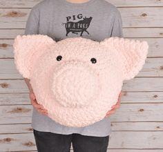 a person holding a pink pig pillow in front of their face