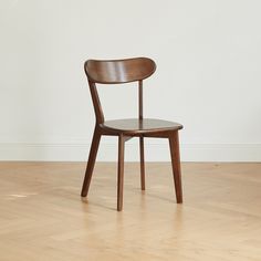 a wooden chair sitting on top of a hard wood floor next to a white wall